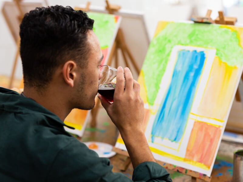 man sipping wine in front of artwork